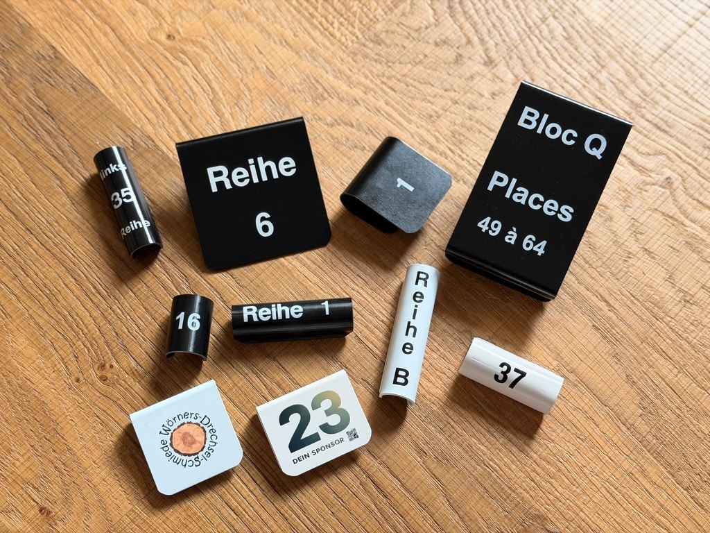 Stuhlnummern, Reihenschilder und Rundrohr-Clips von woerner.systems in verschiedenen Bauformen