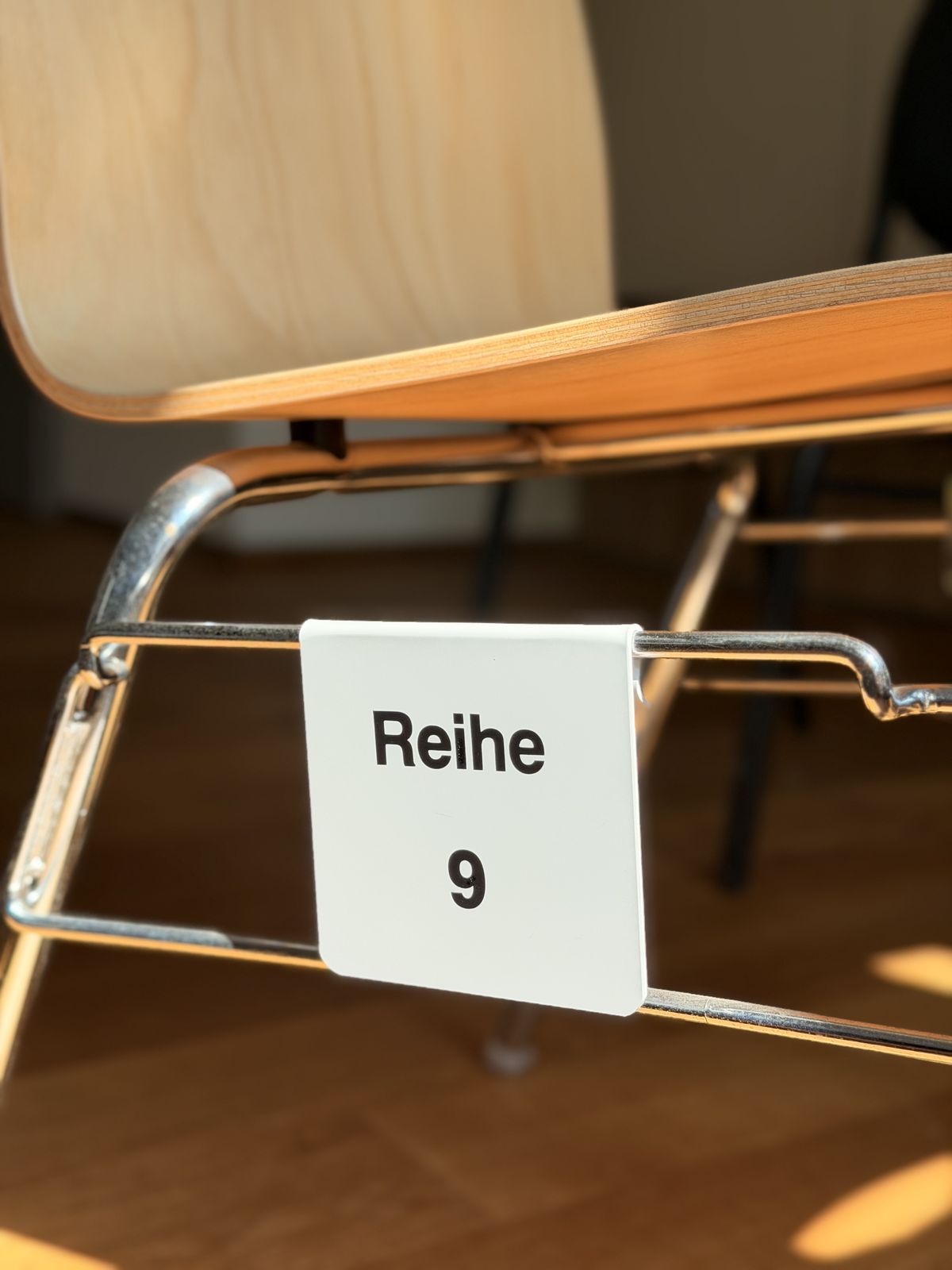 White row sign “Reihe 9” mounted on a chair frame