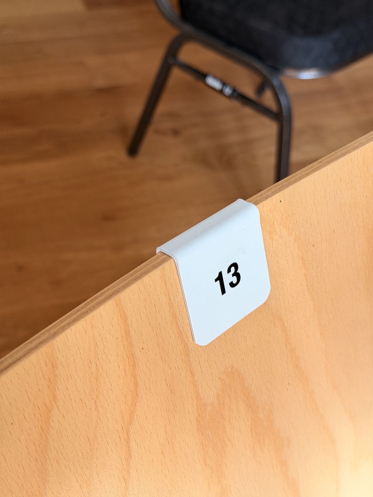 White clip-on chair number 13 on a wooden backrest